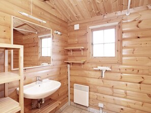 A wooden cabin bathroom with a sink, mirror, two windows, and a heater. - Seaside Haven in Graerup - By Traum Ferienwohnungen (Oksbol)