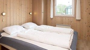 A wooden-paneled room with a bed, two bedside lamps, and a window with curtains. - 6 Person Holiday Home in Sjolund-by Traum (Sjølund)