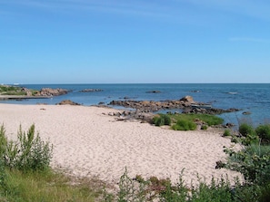 A beach with a sandy shore, rocky outcrops, and calm sea under a clear sky. - 2 Person Holiday Home in Allinge (Allinge)