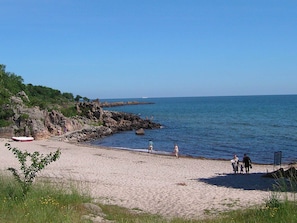 A beach with rocky outcrops, a clear sky, and a calm sea.