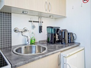 A kitchen with a stainless steel sink, a coffee maker, a kettle, and a dish soap bottle. - 2 Person Holiday Home in Allinge (Allinge)