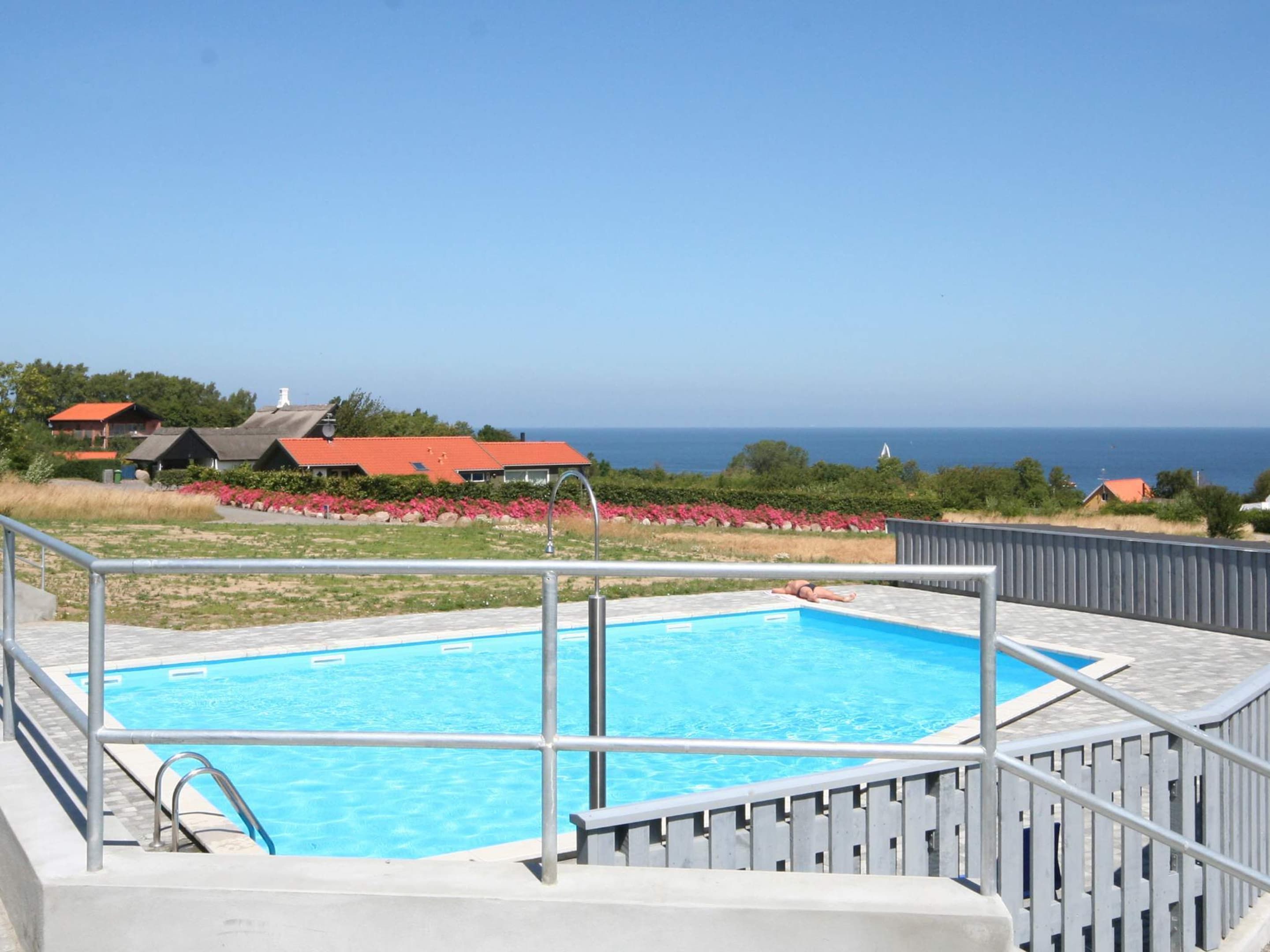 Une piscine avec vue sur la mer et des maisons en arrière-plan.