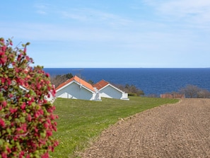 A coastal property with white buildings, a clear view of the sea, and a grassy area.