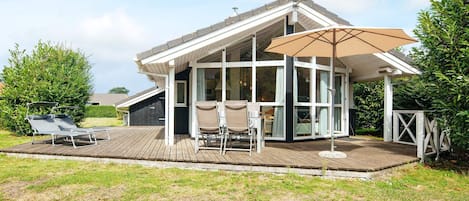 A modern house with a covered patio, a satellite dish, and outdoor furniture.