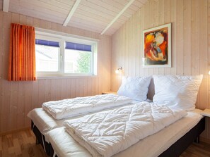 A bedroom with a bed, two bedside tables, a window with curtains, and a painting on the wall. - Holiday Home in Groemitz (Groemitz)