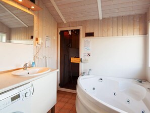 A bathroom with a sink, a large bathtub, a shower area, and a wooden ceiling.