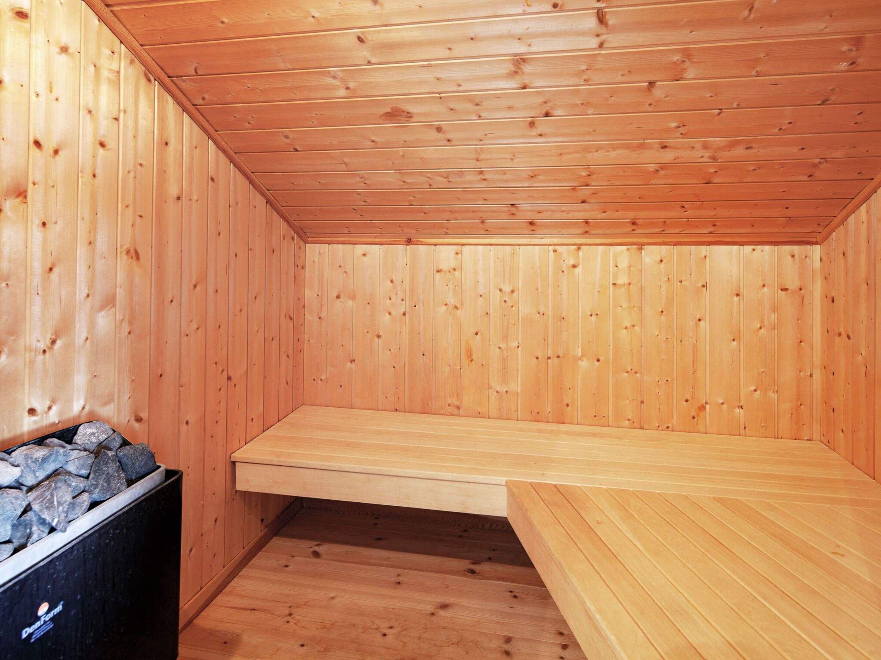 L’intérieur d’un chalet en bois, avec un plafond en pente, un banc et une cheminée.