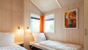 A room with two beds, a window with curtains, and a painting on the wall. - Holiday Home in Groemitz (Groemitz)