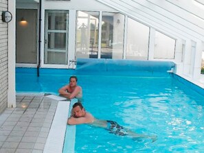 Uma piscina com deck revestido e porta de vidro dando acesso à área da piscina.