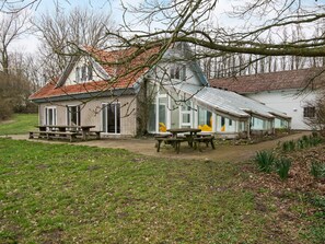 A building with a brick exterior and a tiled roof, featuring a patio area with benches and a clear view of the surrounding landscape. - 16 Person Holiday Home in Aabenraa (Aabenraa)