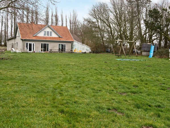 A house with a red-tiled roof, a front porch, and a grassy yard.