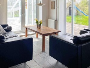 A modern living room with a sofa, a table with a plant, and large glass doors leading to an outdoor area with a slide.