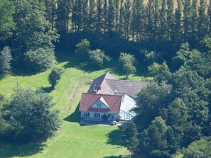 A house surrounded by a forest with a sloped roof and a front porch. - 16 Person Holiday Home in Aabenraa (Aabenraa)