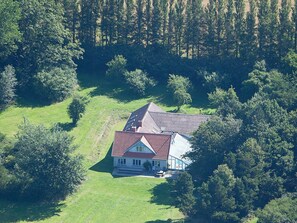 A house surrounded by trees, with a sloped roof and a front porch. - 16 Person Holiday Home in Aabenraa (Aabenraa)