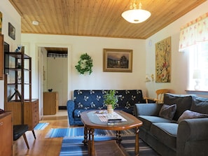 Un salon avec un plafond en bois, un canapé, une table basse et une bibliothèque.