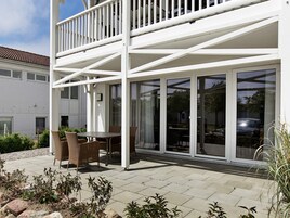 Un edificio de dos pisos con balcón y un patio.