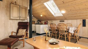 Un intérieur en bois comprenant une table à manger, des chaises, un canapé et un coin cuisine.