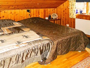 Une chambre à coucher avec un lit, des murs en bois, un radiateur et une petite table sur laquelle sont posés divers objets.