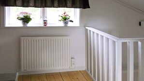A room with a wooden floor, white walls, a window with two potted plants, and a white railing. - 4 Person Holiday Home in Rattvik (Rattvik)