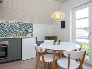 A compact kitchen with a coffee maker, a refrigerator, and a dining area with a round table and chairs.