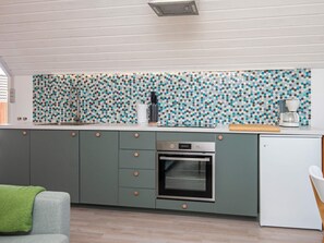 A modern kitchen with a built-in oven, a coffee maker, and a patterned backsplash. - 5 Person Holiday Home in Romo-by Traum (Rømø)