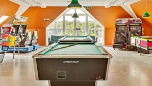 A pool table in a room with orange walls, arcade games, and a large window. - 5 Person Holiday Home in Romo-by Traum (Rømø)