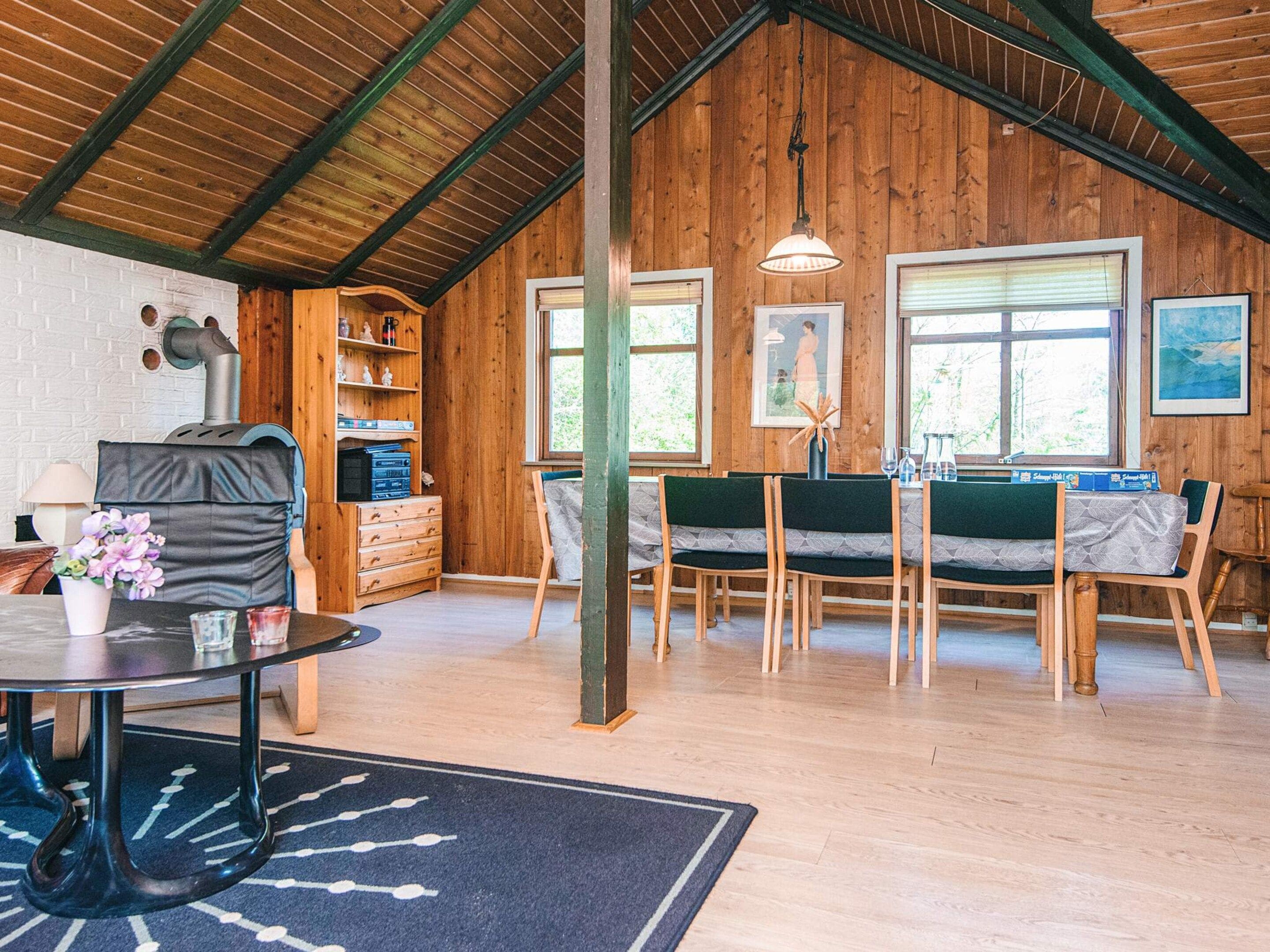 A rustic interior with a dining area, wooden walls, and a fireplace.