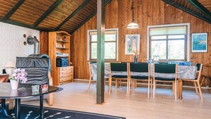 A cozy room with a wooden ceiling, a fireplace, a dining area with chairs and a table, and a window with blinds. - 7 Person Holiday Home in Toftlund (Toftlund)