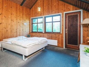 A wooden-paneled room with a bed, a window, and a door. - 7 Person Holiday Home in Toftlund (Toftlund)