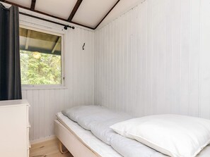 A small, single-bed room with a window, wooden floor, and a white wardrobe. - 4 Person Holiday Home in Skibby (Skibby)