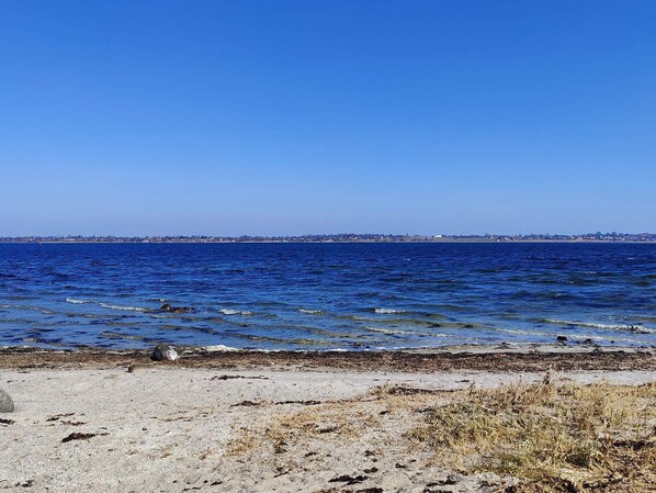 A beach with clear blue water and a distant shoreline. - 4 Person Holiday Home in Skibby (Skibby)