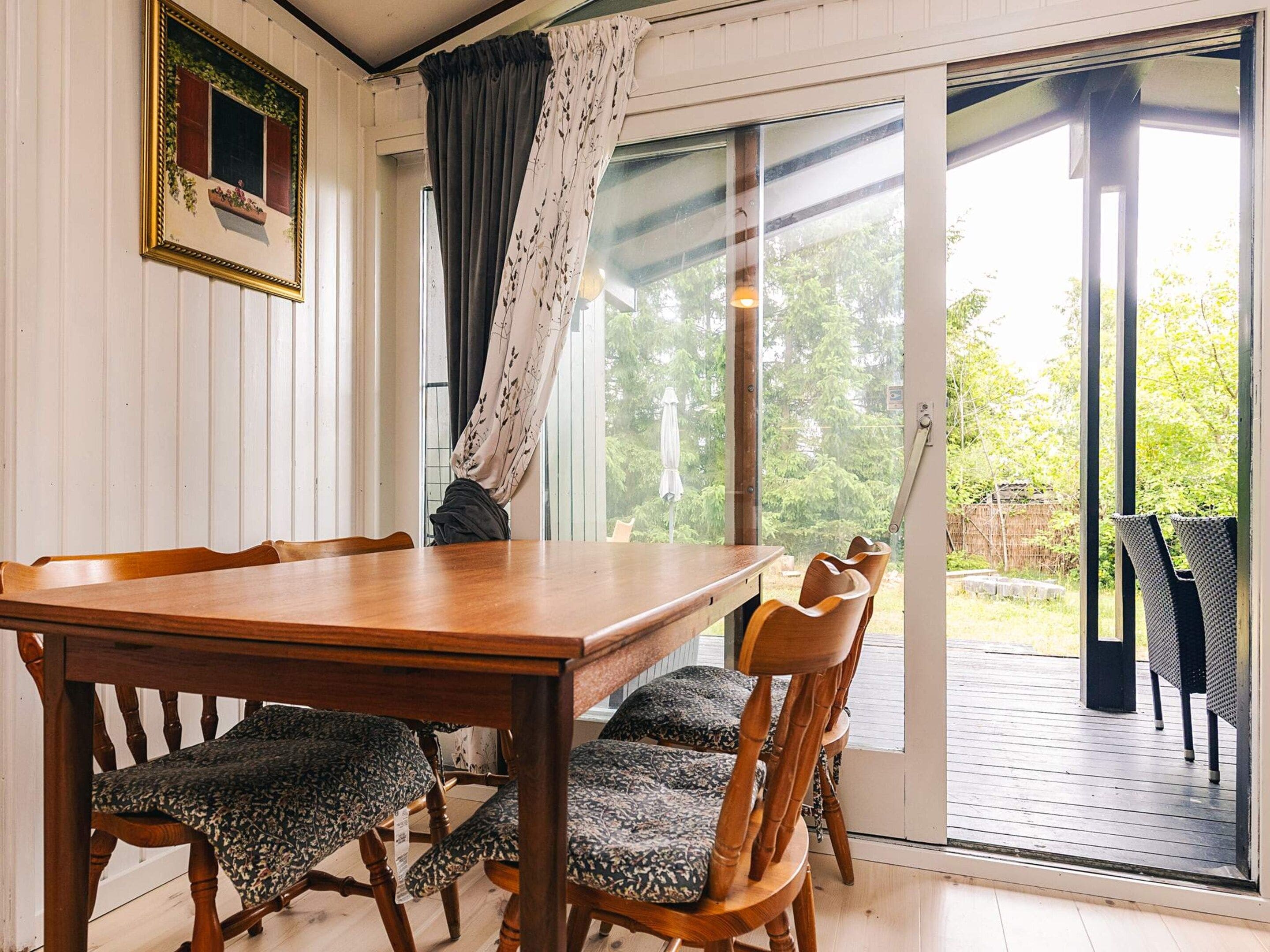 A dining area with a wooden table and chairs, a sliding glass door leading to an outdoor deck.