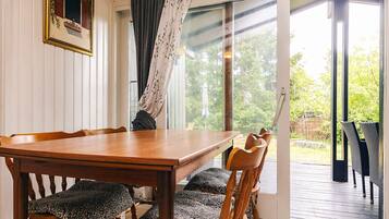 A dining area with a wooden table and chairs, a sliding glass door leading to an outdoor deck.