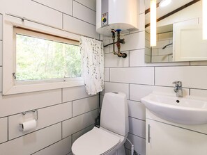 A small bathroom with a toilet, a sink, a window with a curtain, and a mirror. - 4 Person Holiday Home in Skibby (Skibby)