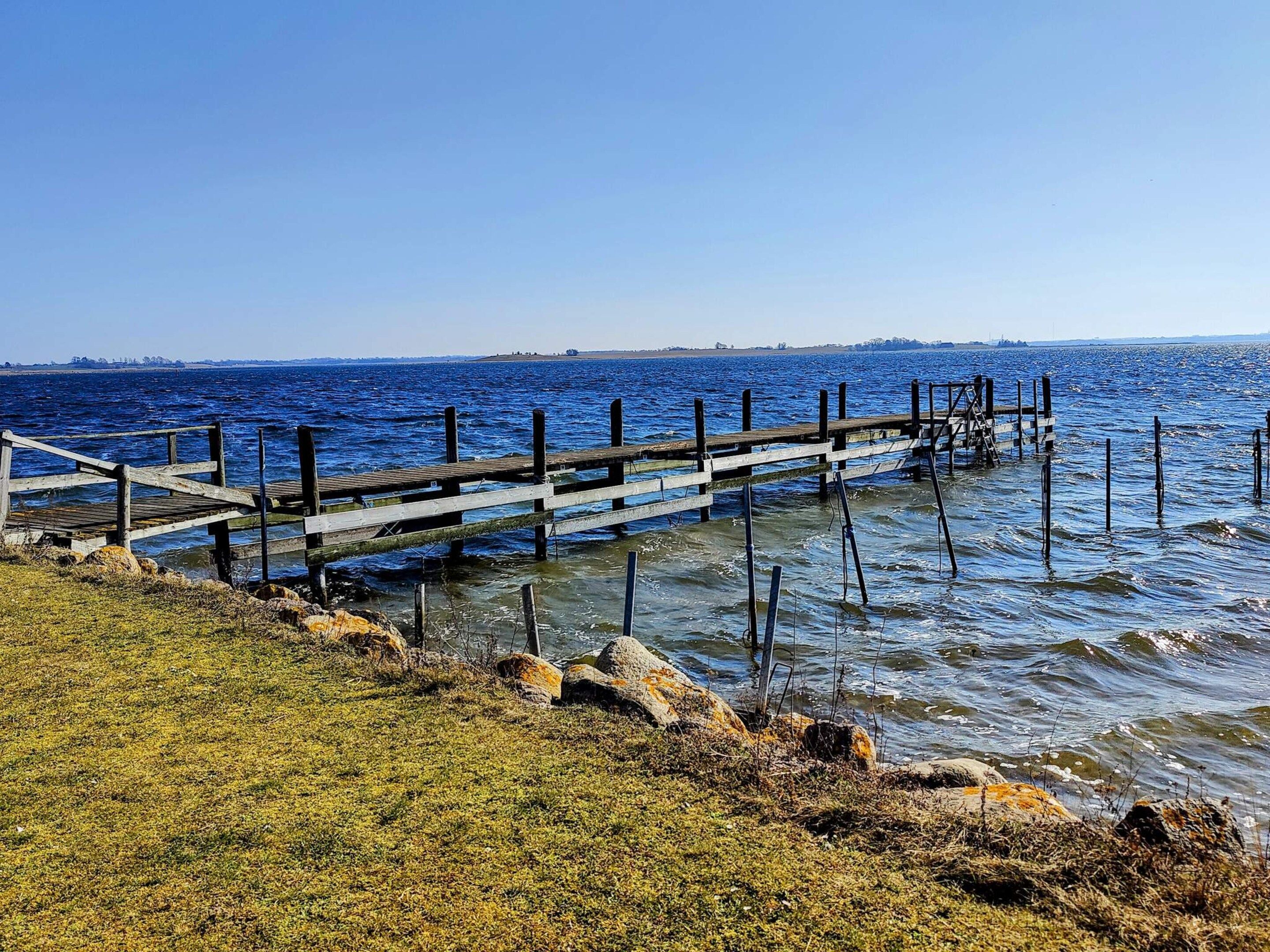 A wooden pier extending into a body of water with a clear sky above.