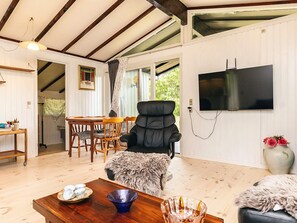 A room with a wooden dining table, a black chair, a television, and a large window. - 4 Person Holiday Home in Skibby (Skibby)