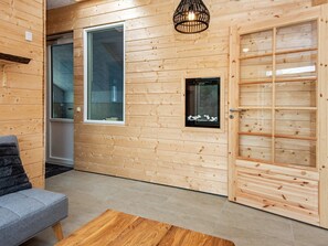 A wooden interior with a sofa, a small table, and a door with a grid pattern. - 8 Person Holiday Home in Ebeltoft-by Traum (Ebeltoft)
