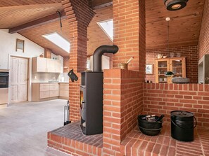 A kitchen with a brick fireplace, wooden cabinets, and a tiled floor.