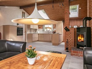 A modern kitchen with wooden cabinets, a central island, and a brick fireplace.