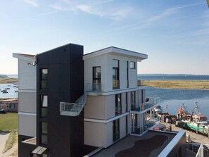 A modern two-story building with a balcony overlooking a marina.