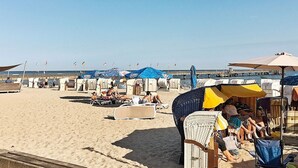 A beach with sun loungers and umbrellas, a pier in the background, and clear skies. - Holiday Home in GroÃŸenbrode (Grossenbrode)