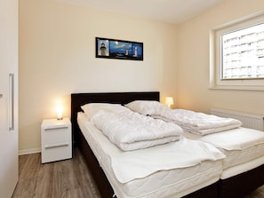 Ein Schlafzimmer mit einem Bett, Nachttischen, einem Fenster mit Blick und einem gerahmten Bild an der Wand.