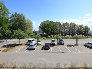 Ein Parkplatz mit mehreren Autos, Bäumen und blauem Himmel.