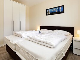 A hotel room with a bed, a nightstand, a framed picture on the wall, and a wardrobe.