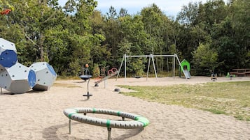 Ein Spielplatz mit Klettergerüsten, Schaukeln und einer Rutsche.