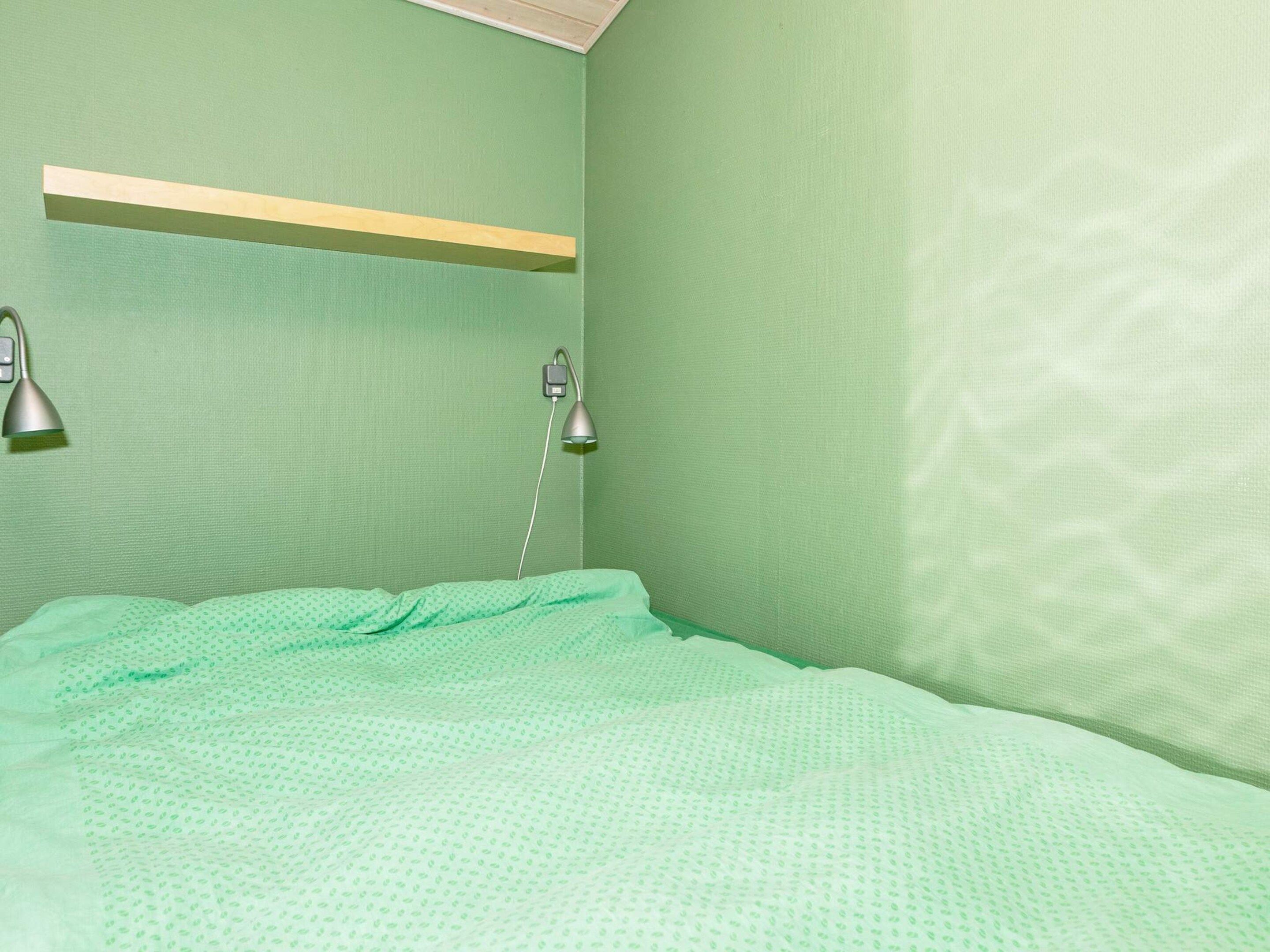 Ein Zimmer mit einem Bett, einem Regal und zwei Wandlampen.