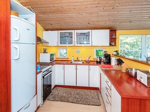 A compact kitchen with white cabinets, a built-in oven, a microwave, and a refrigerator. - Rustic Holiday Home in Logstor near Beach (Logstor)