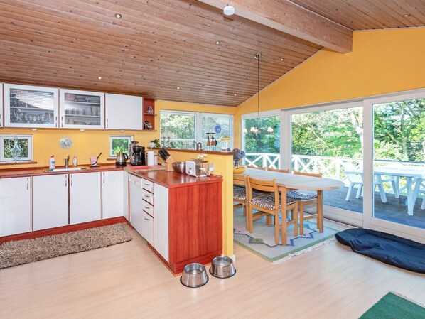Eine moderne Küche mit Holzausstattung, einer zentralen Kochinsel und einem Essbereich mit Tisch und Stühlen.
