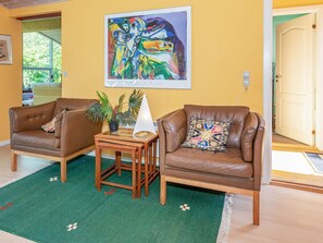 A living room with two leather armchairs, a small wooden table, and a colorful abstract painting on the wall. - Rustic Holiday Home in Logstor near Beach (Logstor)