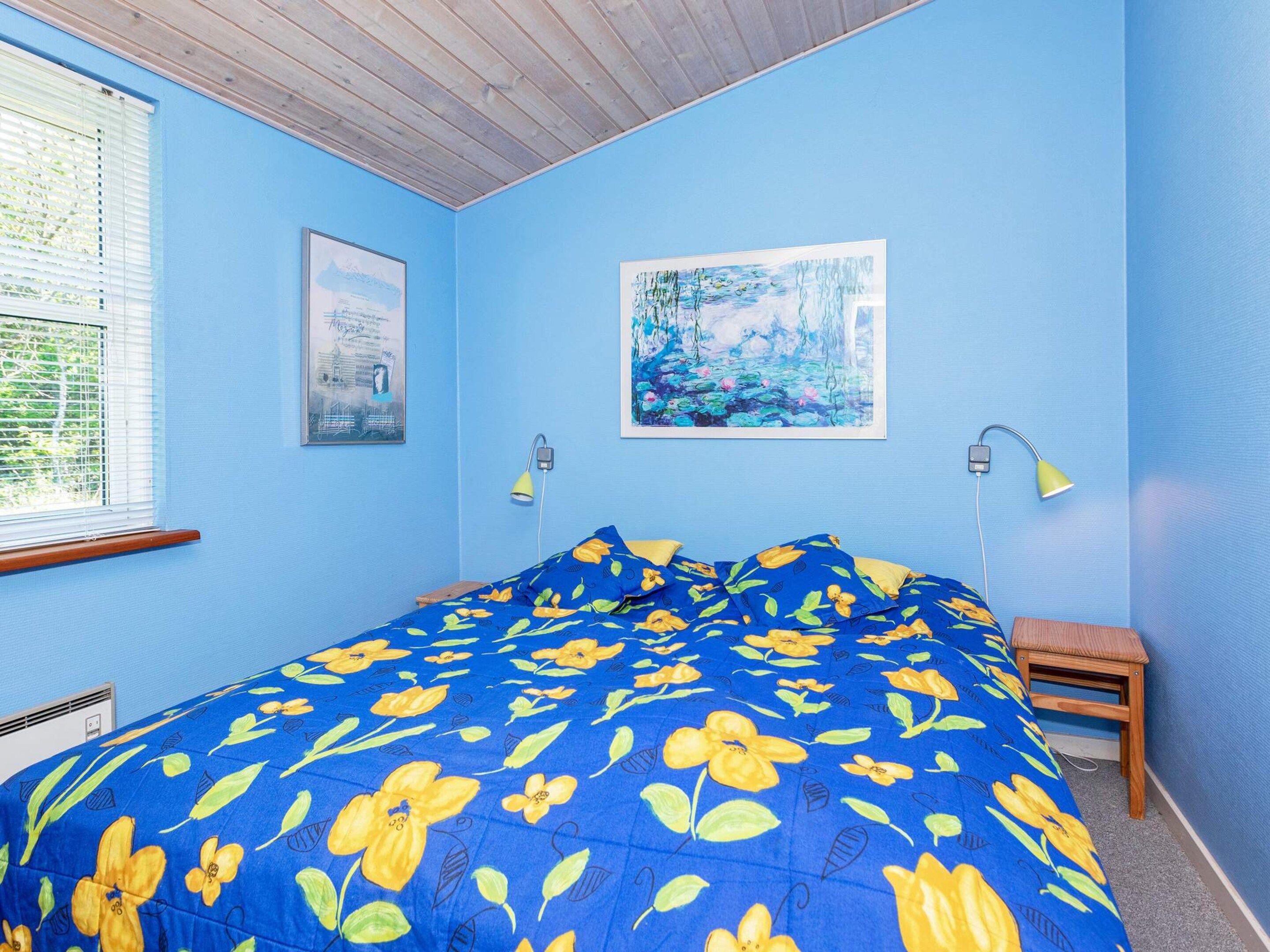 A bedroom with a bed, a window, and two wall-mounted lamps.